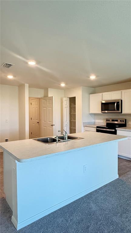 A kitchen features a central island with a sink, white cabinetry, and stainless steel appliances — 2168 CLERMONT STREET, PORT CHARLOTTE, FL