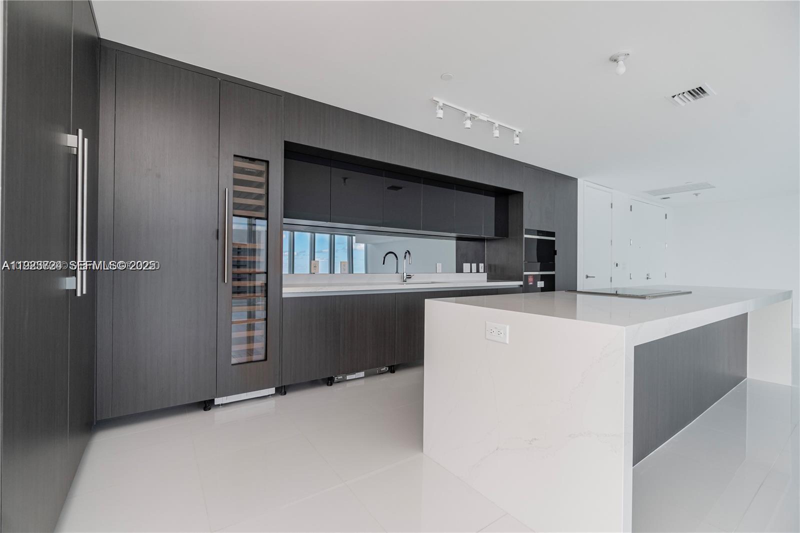A modern kitchen features dark wood cabinetry, a white stone island, and a wine cooler — 851 NE 1st Ave # 4911, Miami FL 33132, MIAMI, FL