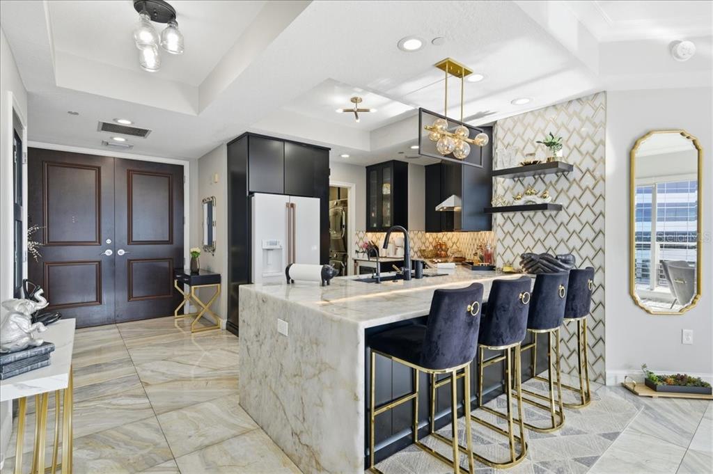 A modern kitchen features a marble waterfall island, black cabinetry, and gold accent lighting — 449 S 12TH STREET UNIT 1804, TAMPA, FL