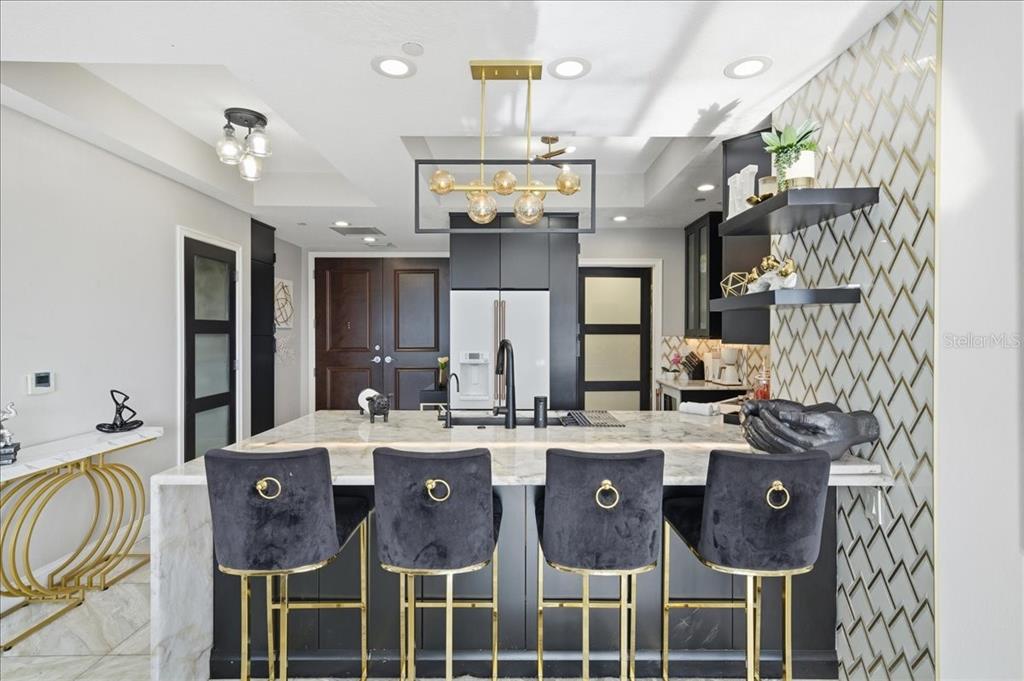 A modern kitchen features a marble-topped island with four black velvet bar stools — 449 S 12TH STREET UNIT 1804, TAMPA, FL