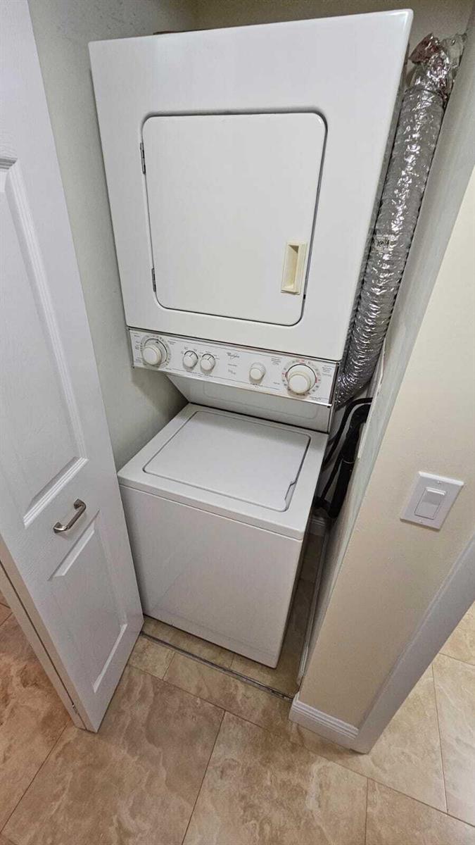 A white stacked washer and dryer unit is installed in a small laundry closet — 205 Foxtail Drive # H3, FL 33415, FL