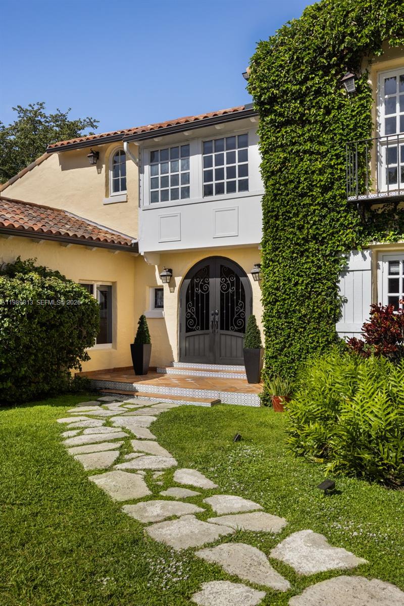 A stone path leads to the arched double front doors of a yellow stucco house — 4206 Alhambra Cir, Coral Gables FL 33146, CORAL GABLES, FL