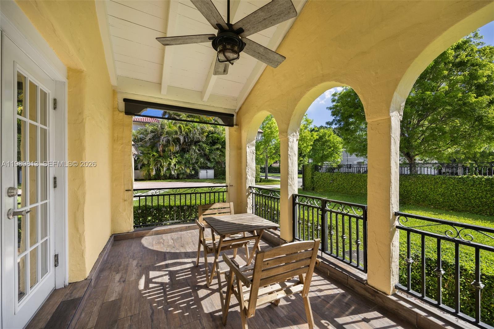 A covered patio features yellow stucco arches, a ceiling fan, and a small wooden table — 4206 Alhambra Cir, Coral Gables FL 33146, CORAL GABLES, FL