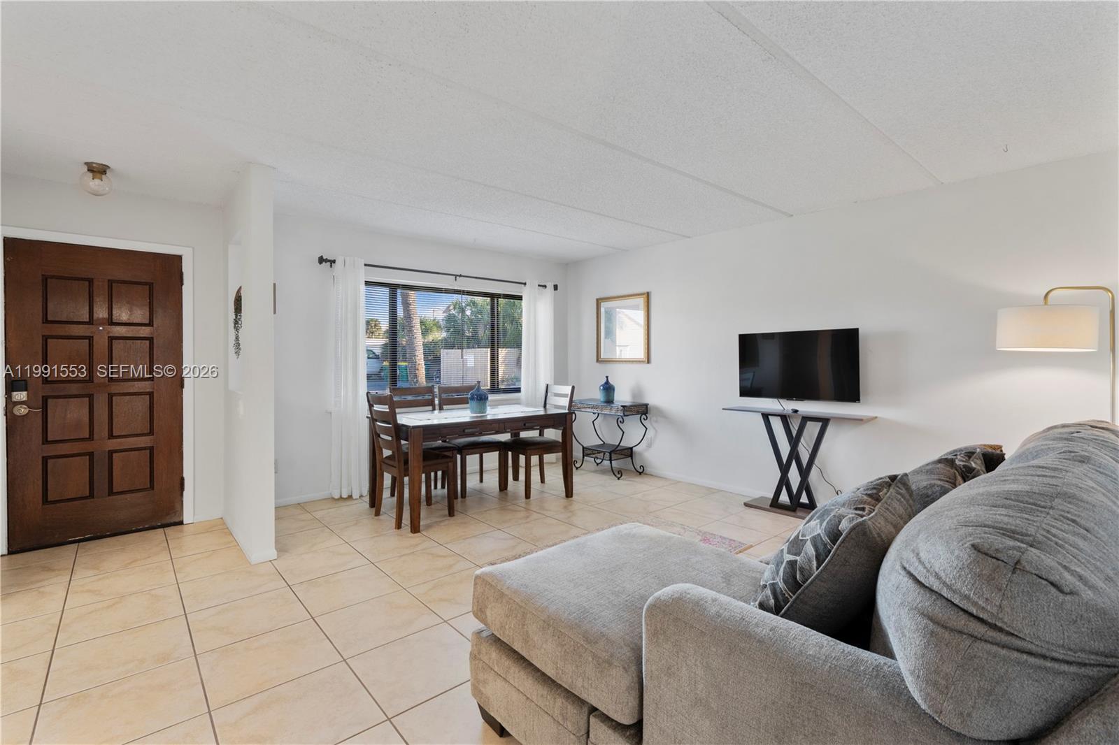 A living and dining area features tile flooring, a gray sectional, and a wooden door — 1145 N Shannon # 39, Indialantic FL 32903, INDIALANTIC, FL