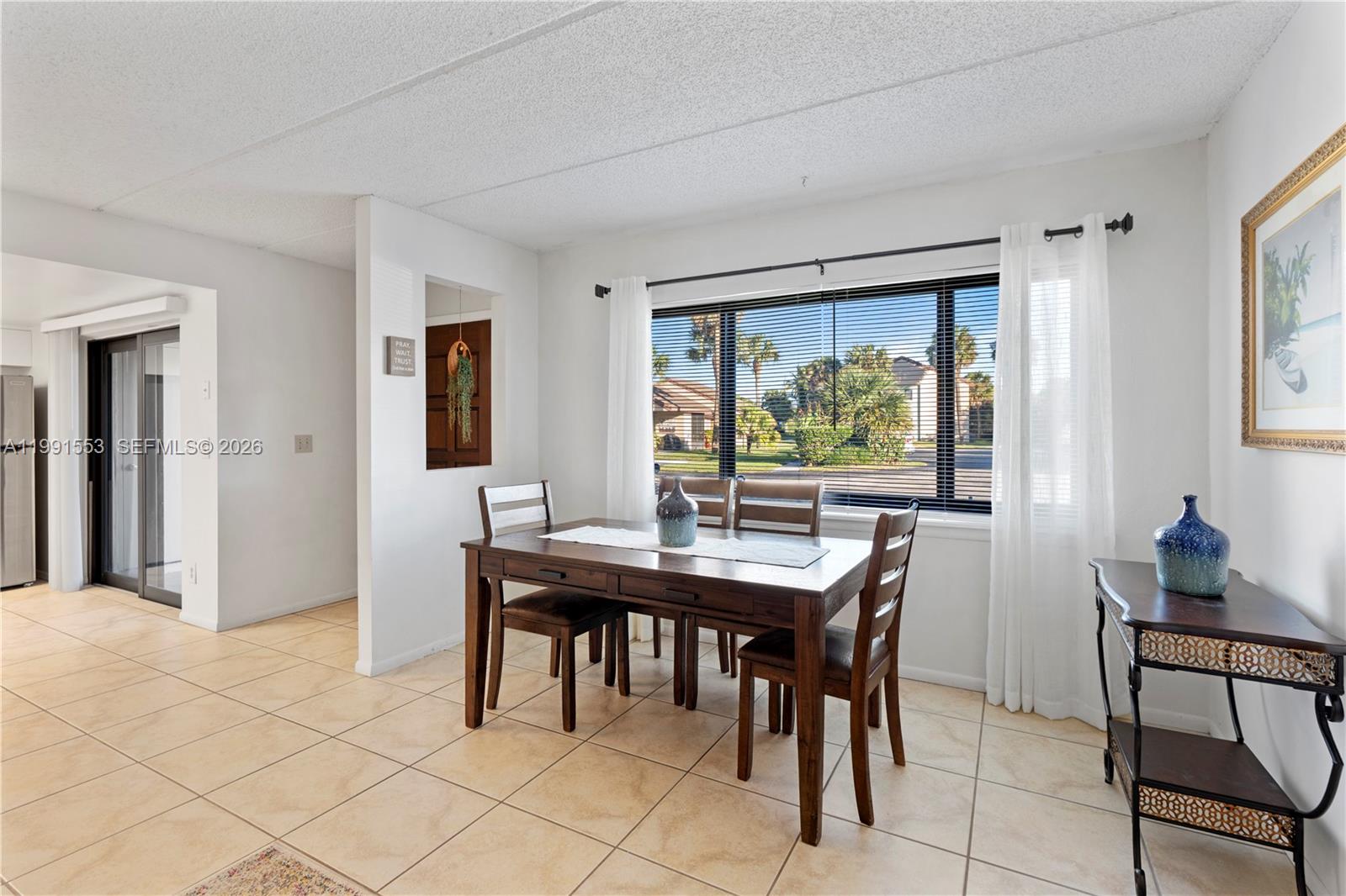 A dining area features a wooden table, four chairs, tile flooring, and a large window — 1145 N Shannon # 39, Indialantic FL 32903, INDIALANTIC, FL