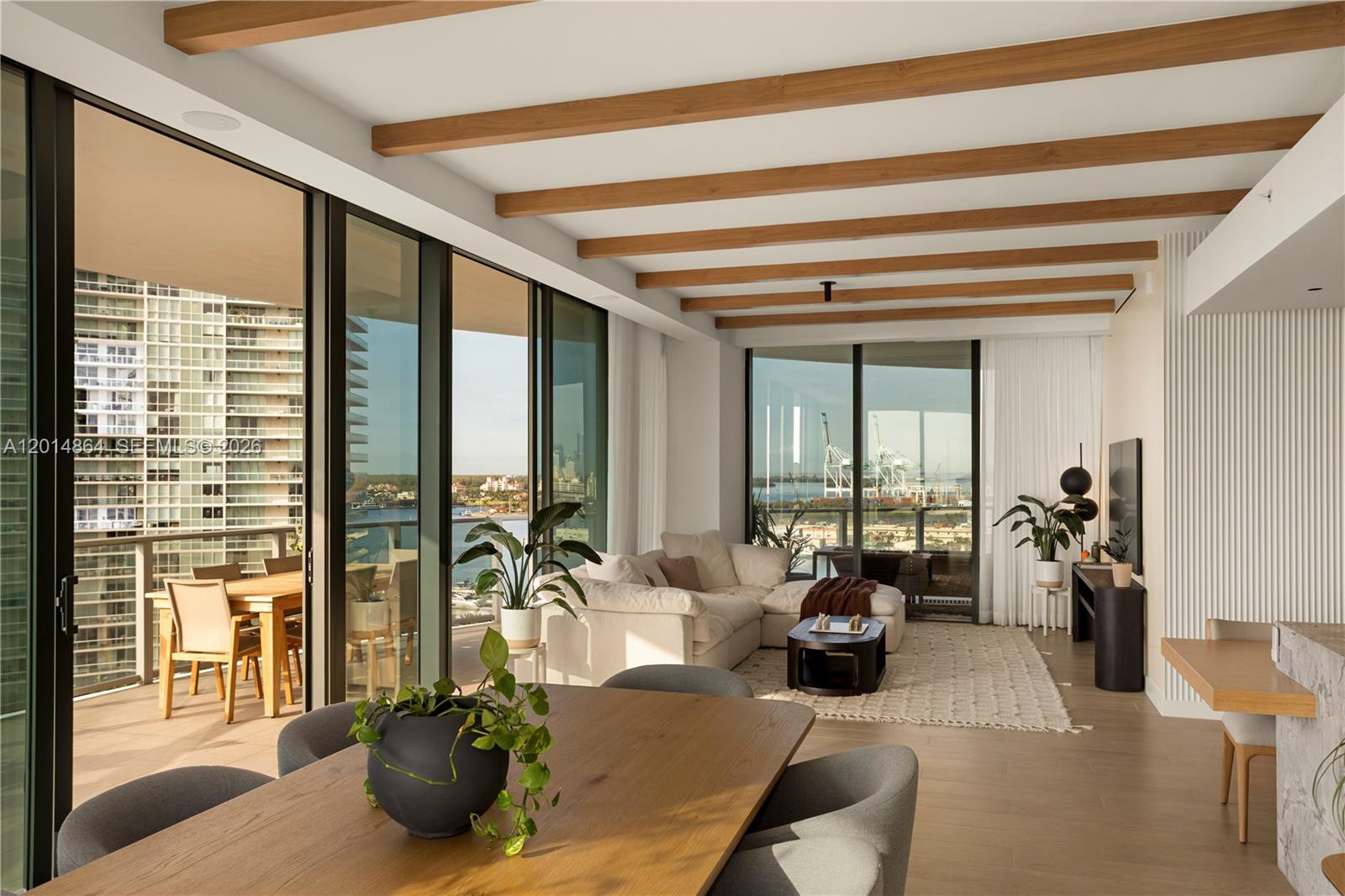 A modern living and dining area features wood ceiling beams, floor-to-ceiling windows, and balcony views — 500 Alton Rd # 1601, Miami Beach FL 33139, MIAMI BEACH, FL