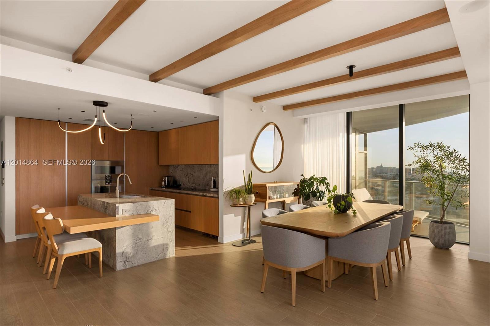 This open-concept dining and kitchen area features wood-beam ceilings, stone countertops, and floor-to-ceiling windows — 500 Alton Rd # 1601, Miami Beach FL 33139, MIAMI BEACH, FL
