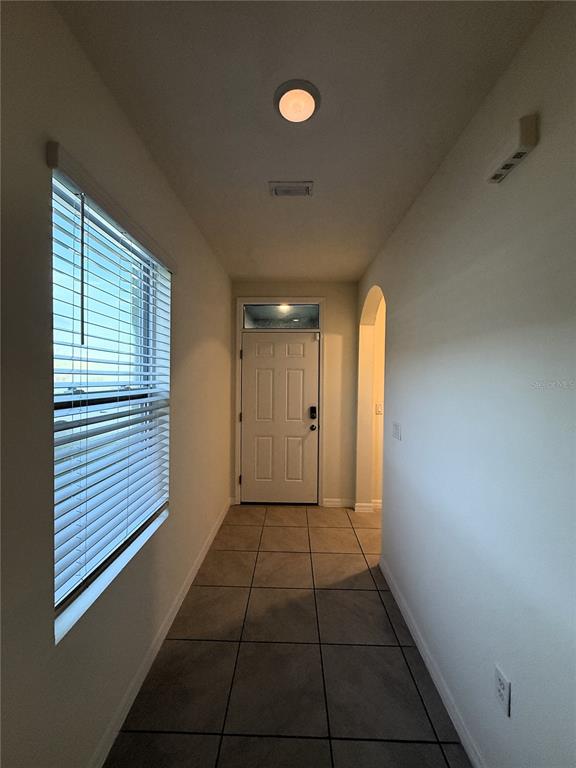 A tiled entryway features a window with blinds, a front door, and an arched doorway — 1064 ANDEAN LANE, DAVENPORT, FL
