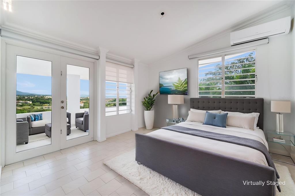 A bedroom with a gray upholstered bed, white tile floors, and a balcony with views — 15 PORT ROAD, HUMACAO, PR