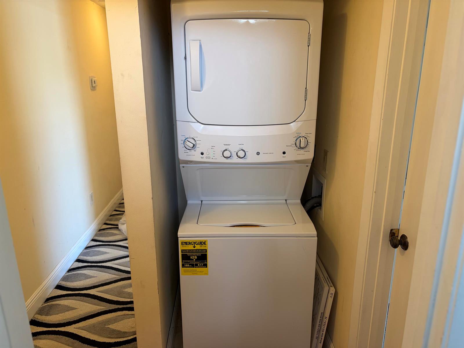 A white stacked washer and dryer unit sits in a small laundry closet — 5654 Golden Eagle Circle, Palm Beach Gardens FL 33418, PALM BEACH GARDENS, FL