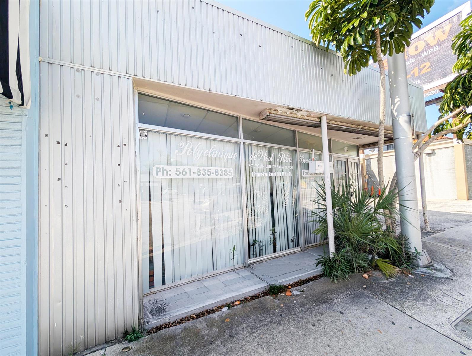 The exterior of a commercial building features a glass storefront with signage and a sidewalk — 734 Belvedere Road, West Palm Beach FL 33405, WEST PALM BEACH, FL