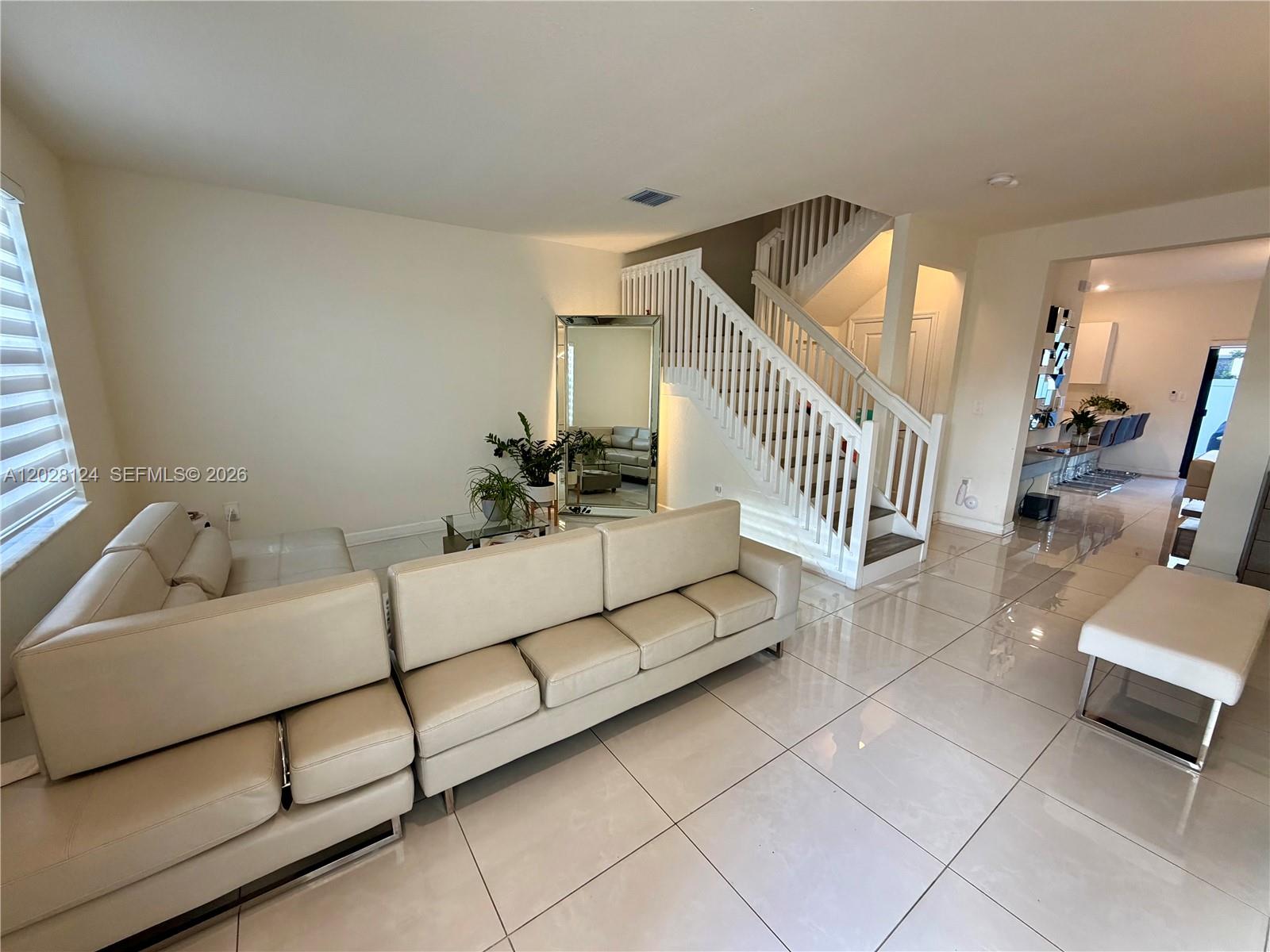 A living room features a large beige sectional sofa, a floor mirror, and a staircase — 11445 W 33rd Ln, Hialeah FL 33018, HIALEAH, FL