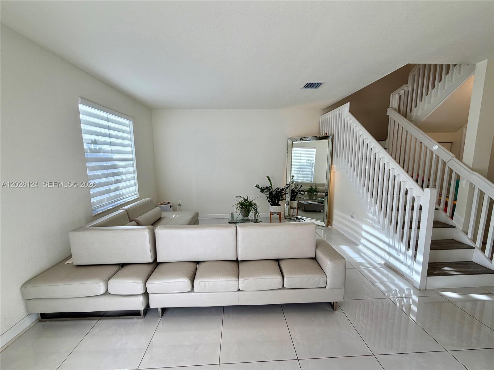 A living room features a large sectional sofa, tile flooring, and a staircase with railings — 11445 W 33rd Ln, Hialeah FL 33018, HIALEAH, FL