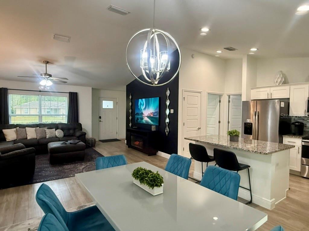 An open-concept living and dining area features a dark accent wall, chandelier, and kitchen island — 5653 PECAN ROAD, OCALA, FL