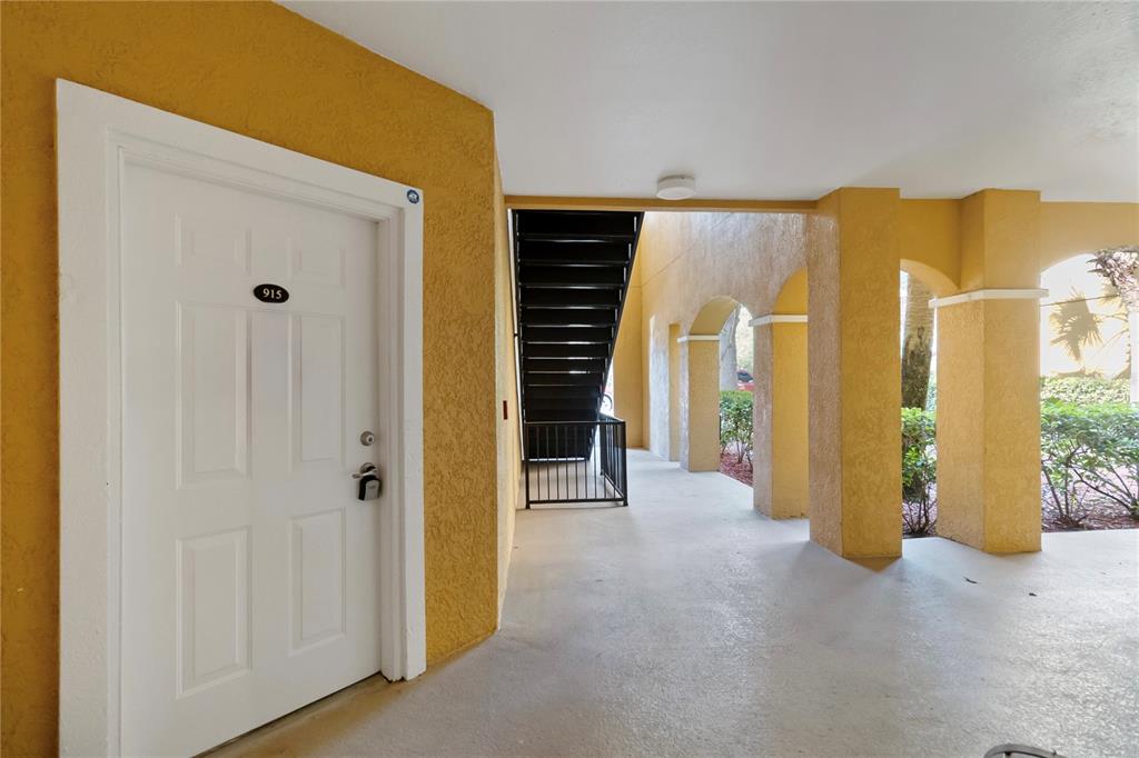 An exterior view shows a white apartment door labeled 915 next to a metal staircase — 3599 CONROY ROAD UNIT 915, ORLANDO, FL