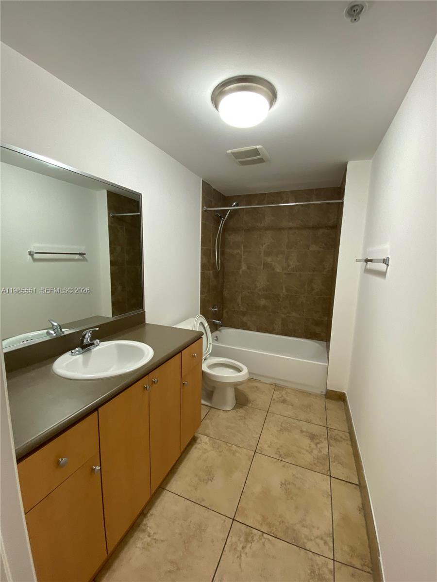 A bathroom features a vanity with a brown countertop, a toilet, and a tiled tub — 435 SW 12th Ave # 605, Miami FL 33130, MIAMI, FL