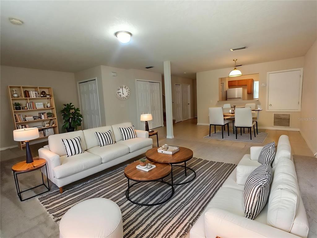 A living room with two white sofas, round wooden coffee tables, and an adjacent dining area — 880 E COLUMBIA AVENUE, KISSIMMEE, FL