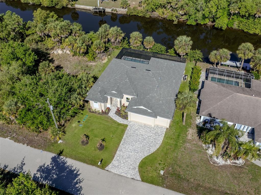 An aerial view shows a house with a paved driveway, pool cage, and canal access — 3423 KNOX TERRACE, PORT CHARLOTTE, FL