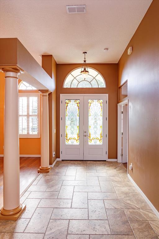 A foyer with tile flooring, two columns, and double front doors featuring decorative stained glass — 3712 CLYDEBANK COURT, APOPKA, FL