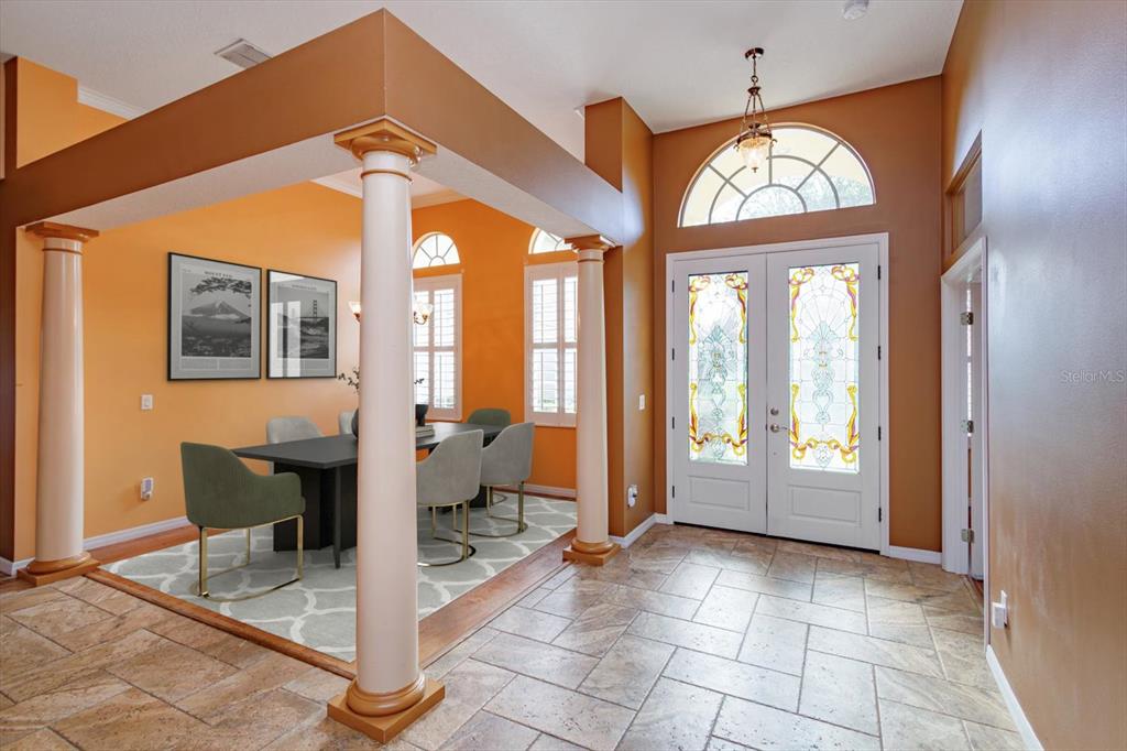 A dining area with columns and a tiled entryway featuring a double front door — 3712 CLYDEBANK COURT, APOPKA, FL