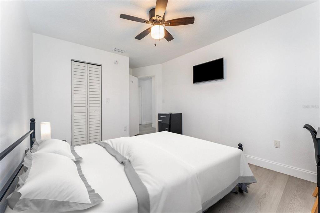 A bedroom features a bed with white bedding, a ceiling fan, and a wall-mounted television — 334 DAGAMA COURT, KISSIMMEE, FL