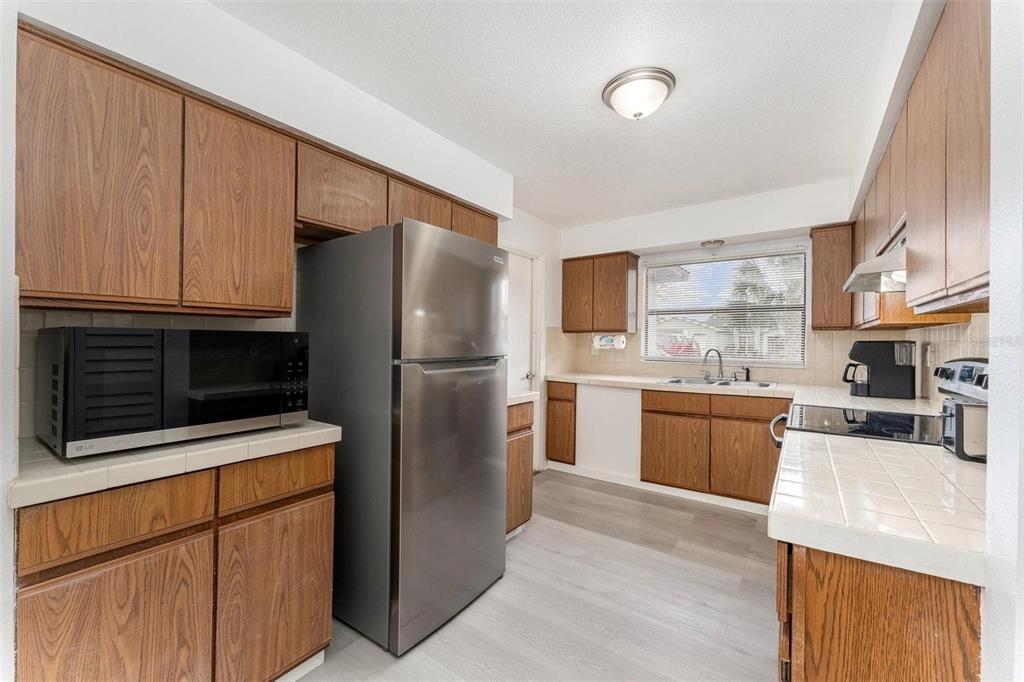 A kitchen features wood cabinets, stainless steel appliances, and white tile countertops — 334 DAGAMA COURT, KISSIMMEE, FL