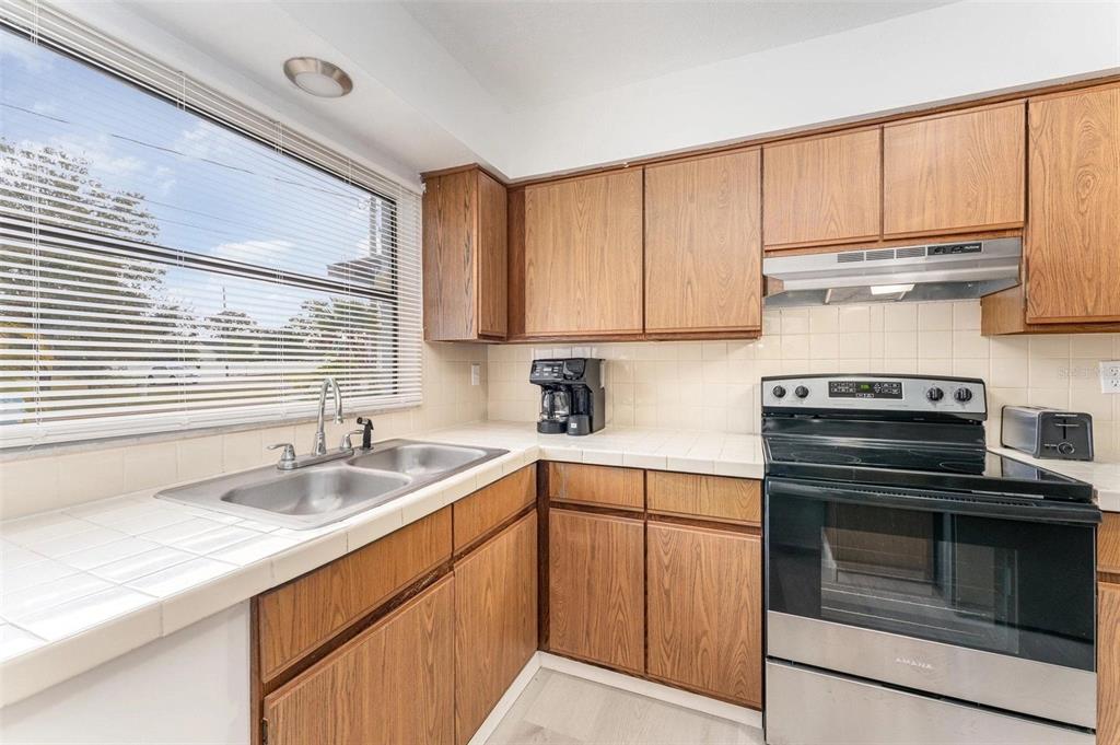A kitchen with wood cabinets, white tiled countertops, a double sink, and stainless steel appliances — 334 DAGAMA COURT, KISSIMMEE, FL