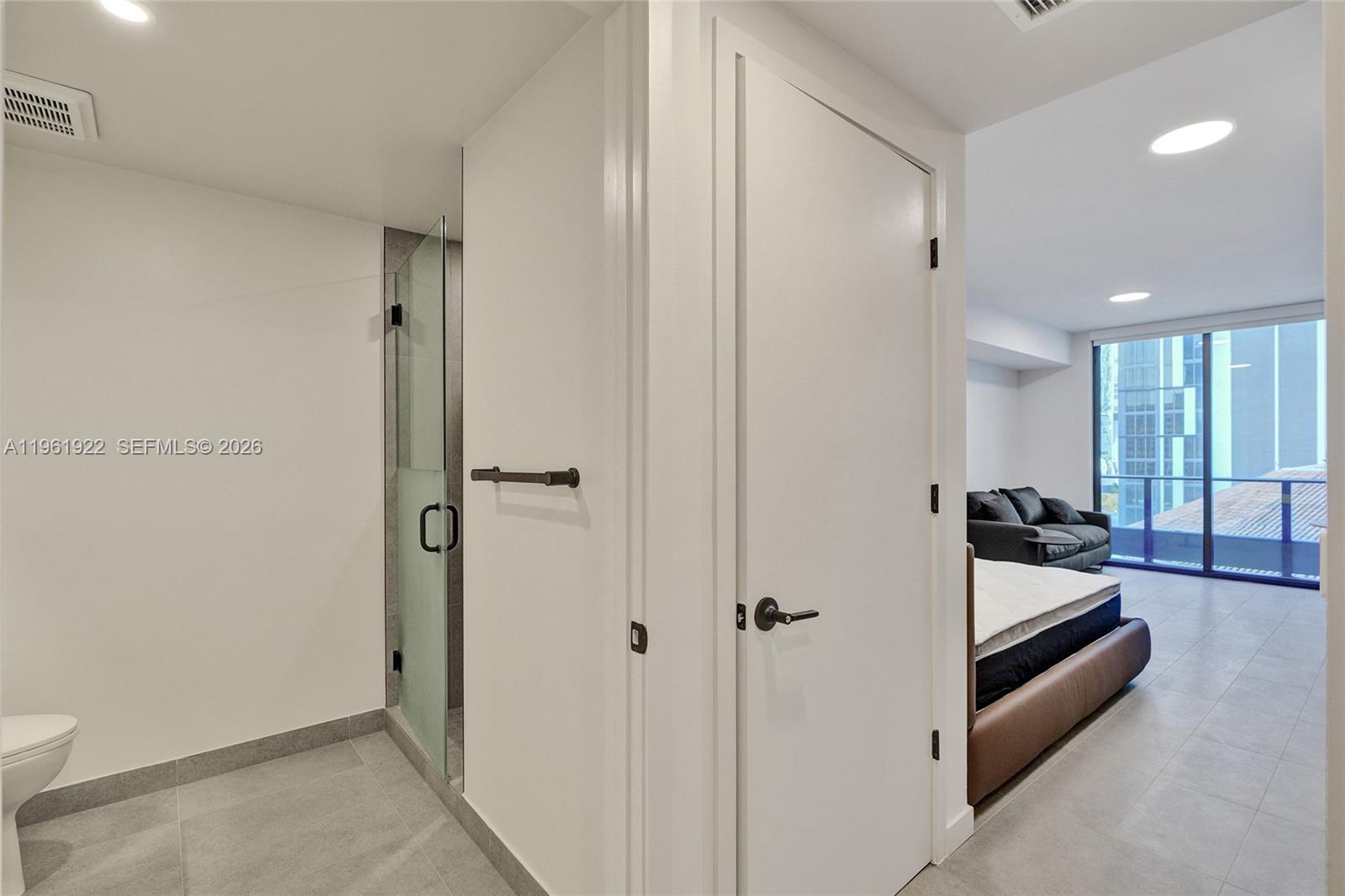 A bathroom with a glass-enclosed shower opens into a bedroom with a balcony view — 121 NE 5th Street # 807, Miami FL 33132, MIAMI, FL