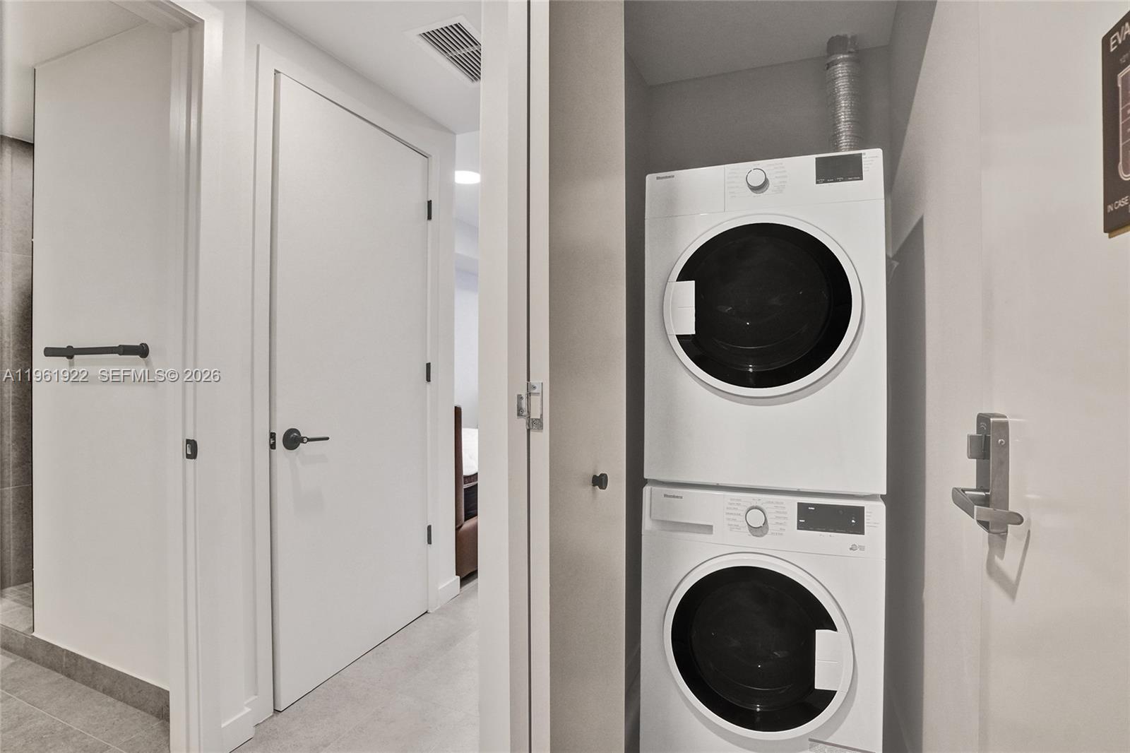 A stacked washer and dryer unit is located in a small closet near a hallway — 121 NE 5th Street # 807, Miami FL 33132, MIAMI, FL