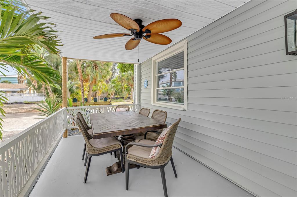 A covered porch features a dining table with chairs, a ceiling fan, and light-colored siding — 134 86TH TERRACE, TREASURE ISLAND, FL