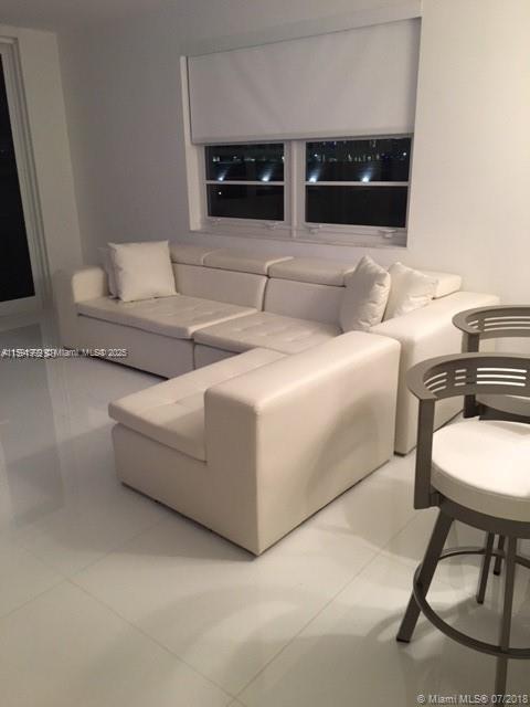 A white sectional sofa sits in a room with white tile floors and a window — 100 LINCOLN RD # 711, Miami Beach FL 33139, MIAMI BEACH, FL