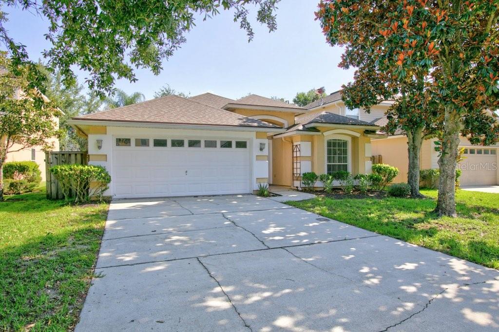 A single-story house with a two-car garage, beige stucco exterior, and a concrete driveway — 828 CRYSTAL SPRING WAY, ST AUGUSTINE, FL