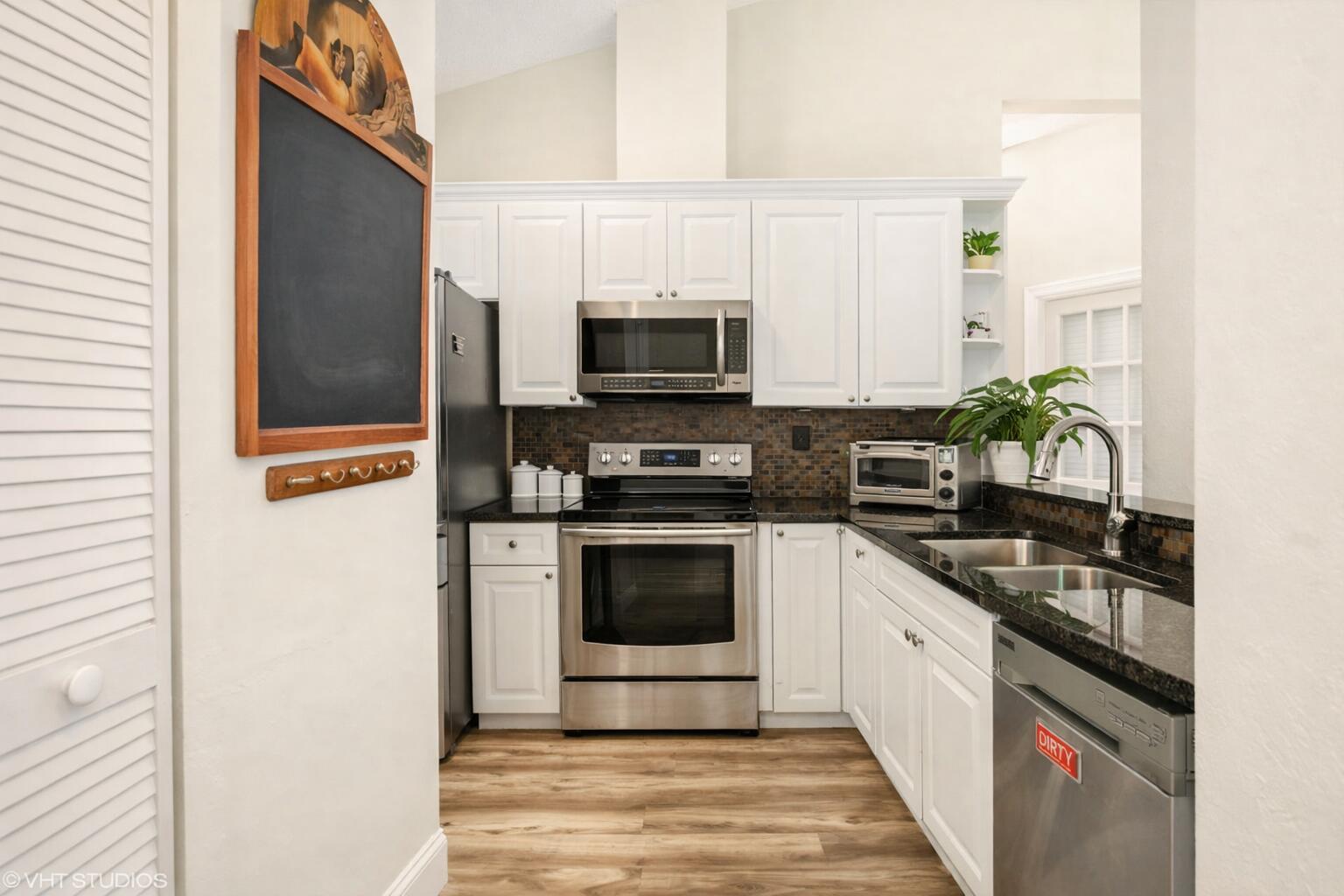 A kitchen with white cabinets, stainless steel appliances, dark countertops, and a chalkboard wall — 805 Harbour Pointe Way # 805, FL 33413, FL