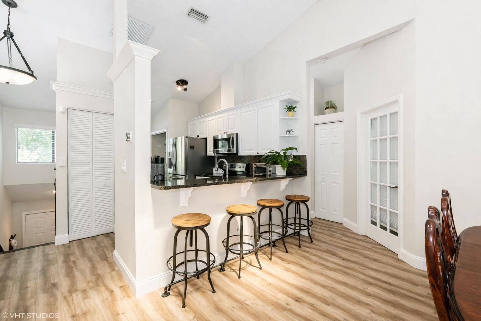 A kitchen features white cabinets, dark countertops, a breakfast bar with stools, and wood flooring — 805 Harbour Pointe Way # 805, FL 33413, FL