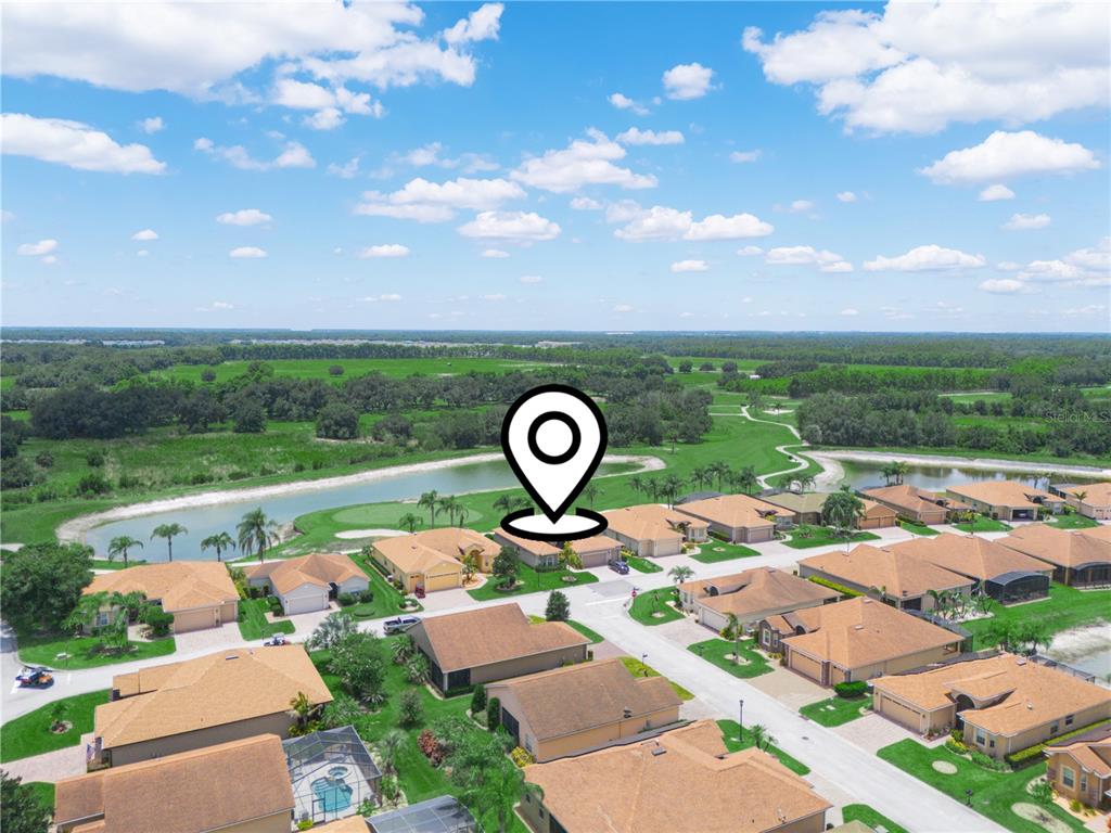 An aerial view shows a suburban neighborhood with houses, a pond, and a golf course — 4052 PHOENICIAN WAY, WINTER HAVEN, FL