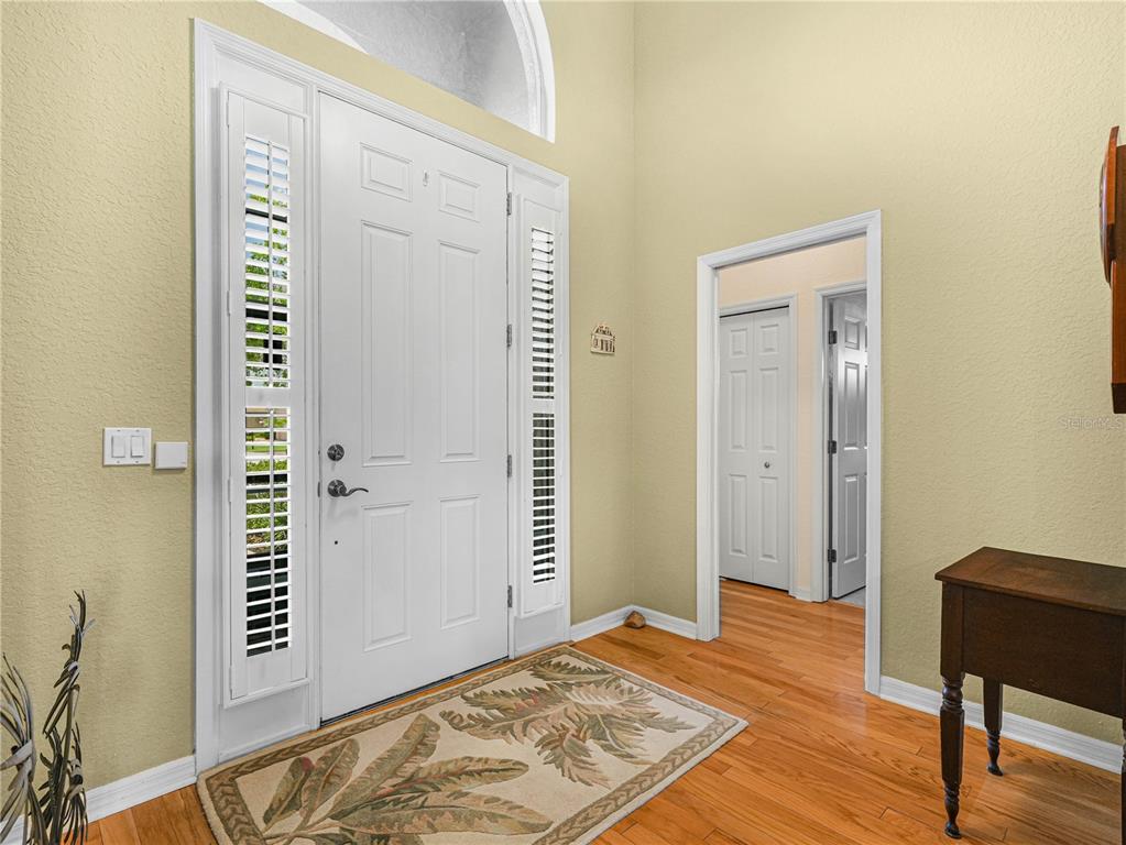 An entryway features a white front door with sidelights, hardwood flooring, and a patterned rug — 4052 PHOENICIAN WAY, WINTER HAVEN, FL
