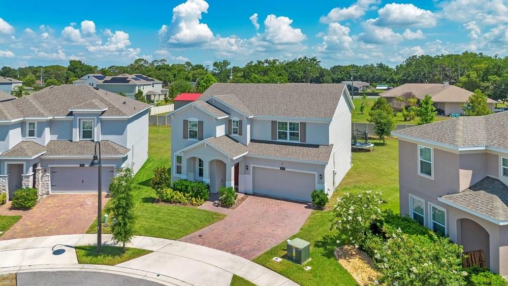 An aerial view of a two-story suburban house with a brick driveway and garage — 5063 HATCHINEHA COURT, ST CLOUD, FL