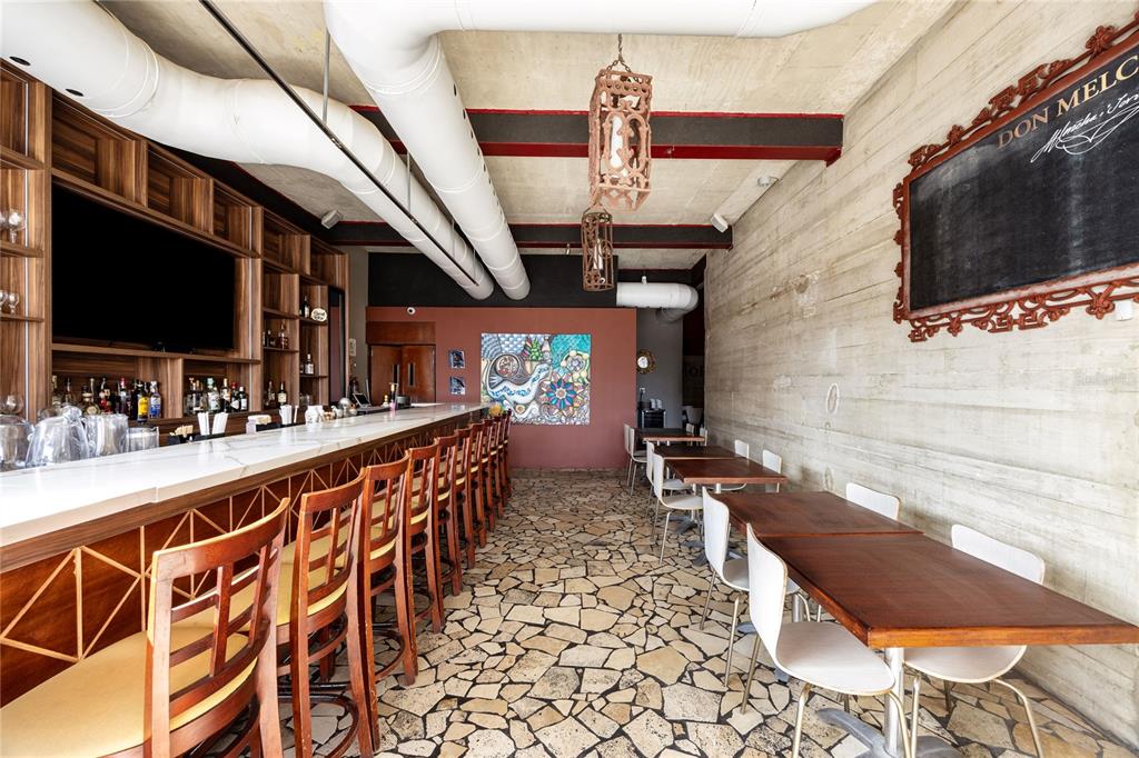 A bar area features a long counter, wooden stools, tables, and exposed ductwork — 1105 MAGDALENA AVENUE UNIT Condal, SAN JUAN, PR