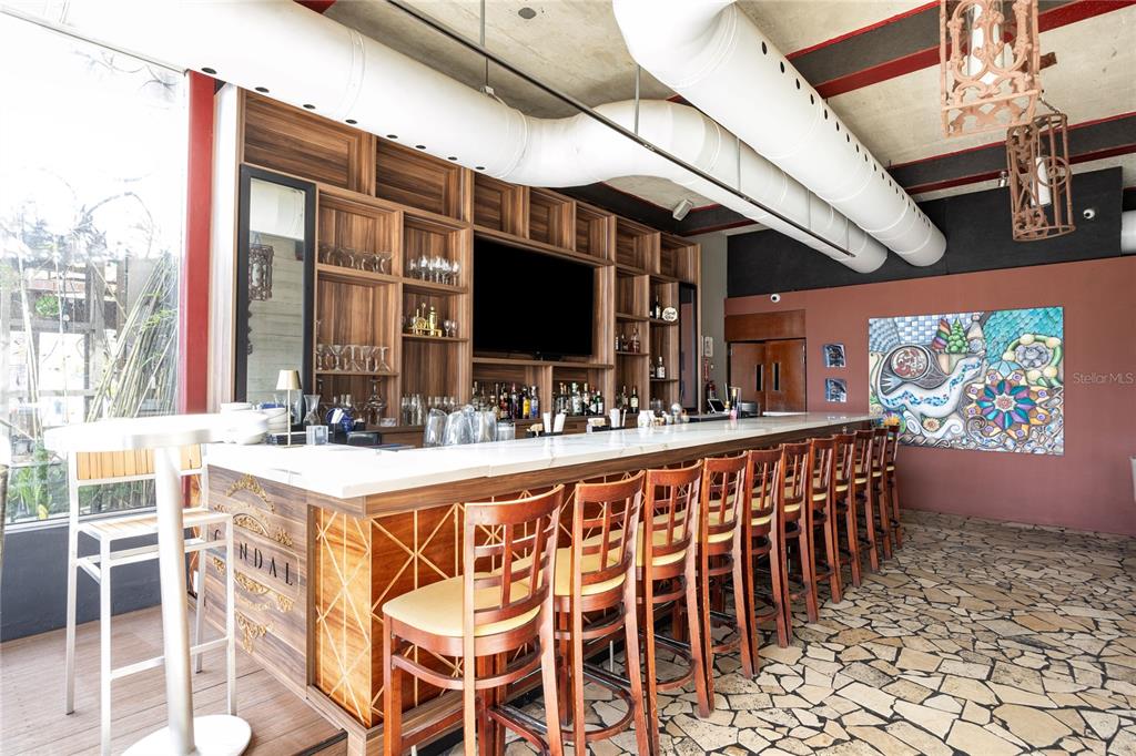 A bar area features a long white counter, wooden stools, shelving, and exposed industrial ductwork — 1105 MAGDALENA AVENUE UNIT Condal, SAN JUAN, PR