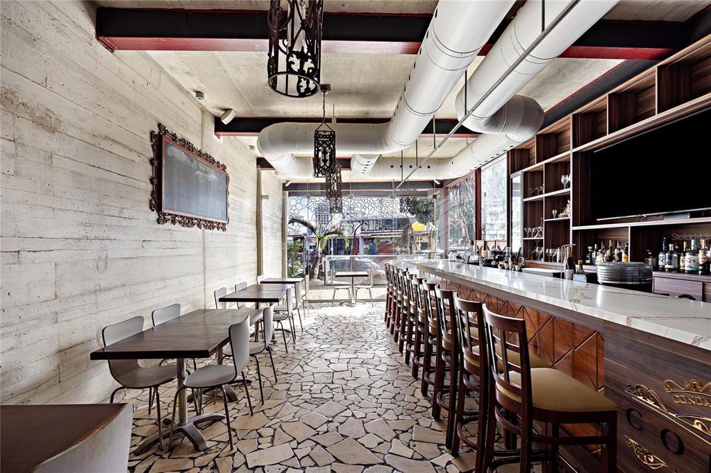 A bar area features a marble-topped counter, wooden stools, stone flooring, and exposed ductwork — 1105 MAGDALENA AVENUE UNIT Condal, SAN JUAN, PR