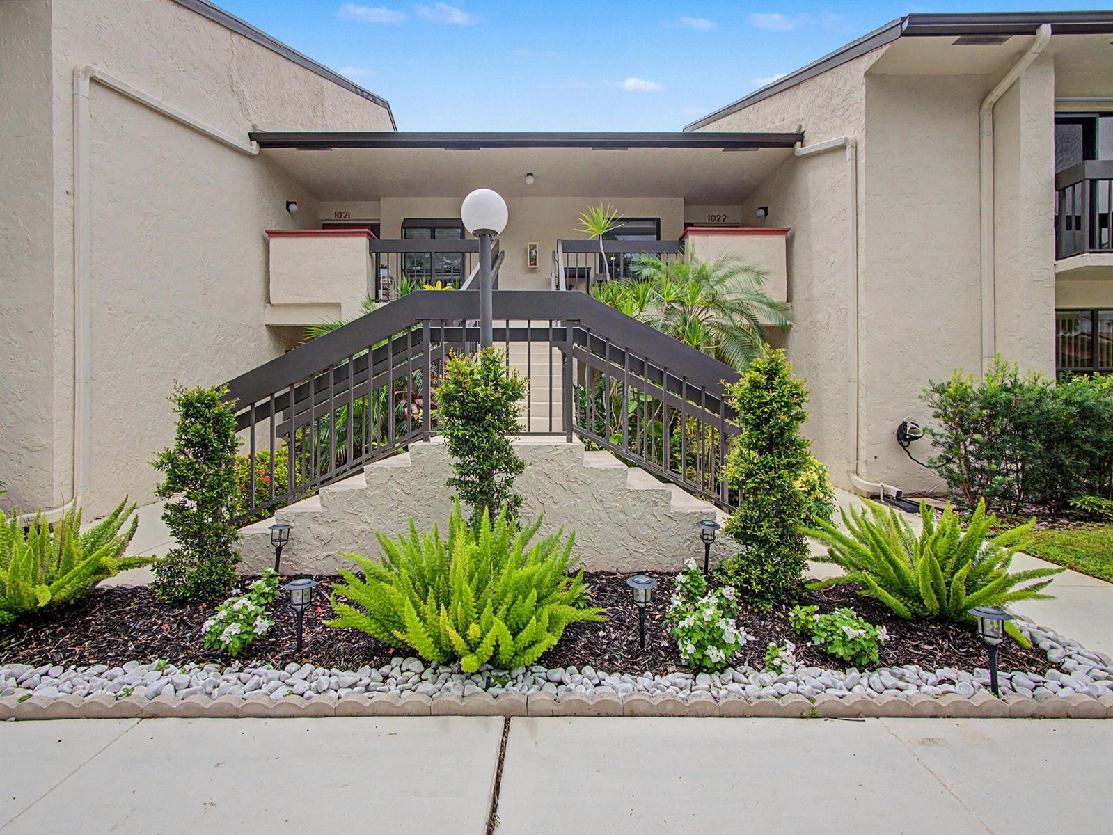 The exterior of a two-story apartment building features a central staircase leading to two units — 5154 Oak Hill Lane # 1022, Delray Beach FL 33484, DELRAY BEACH, FL