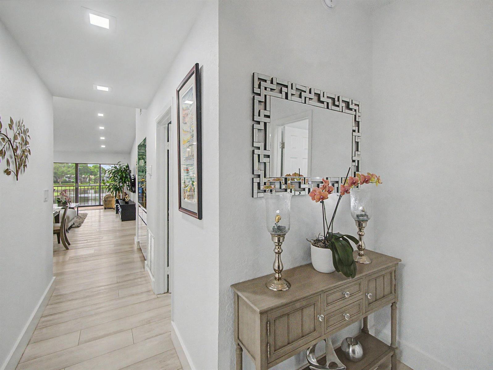 A hallway leads to a living area with a view of a lake through glass doors — 5154 Oak Hill Lane # 1022, Delray Beach FL 33484, DELRAY BEACH, FL