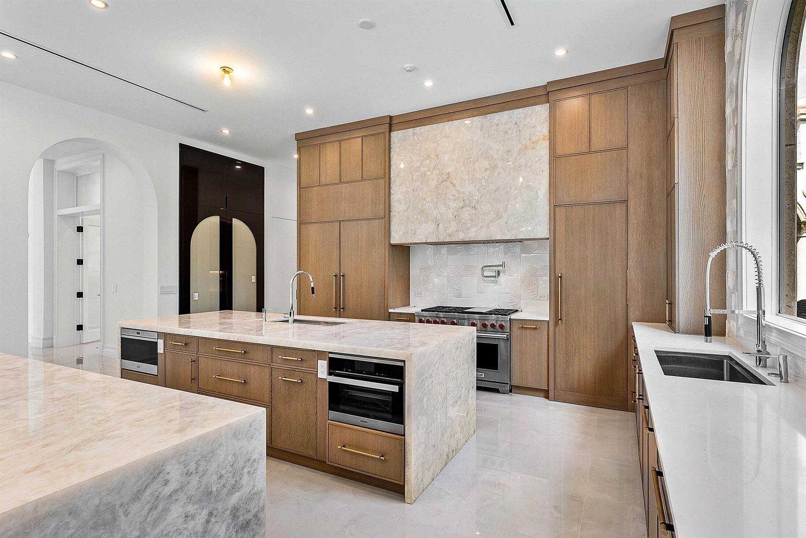 A modern kitchen features light wood cabinetry, marble countertops, a large island, and stainless appliances — 2002 NW 4th Avenue, Delray Beach FL 33444, DELRAY BEACH, FL