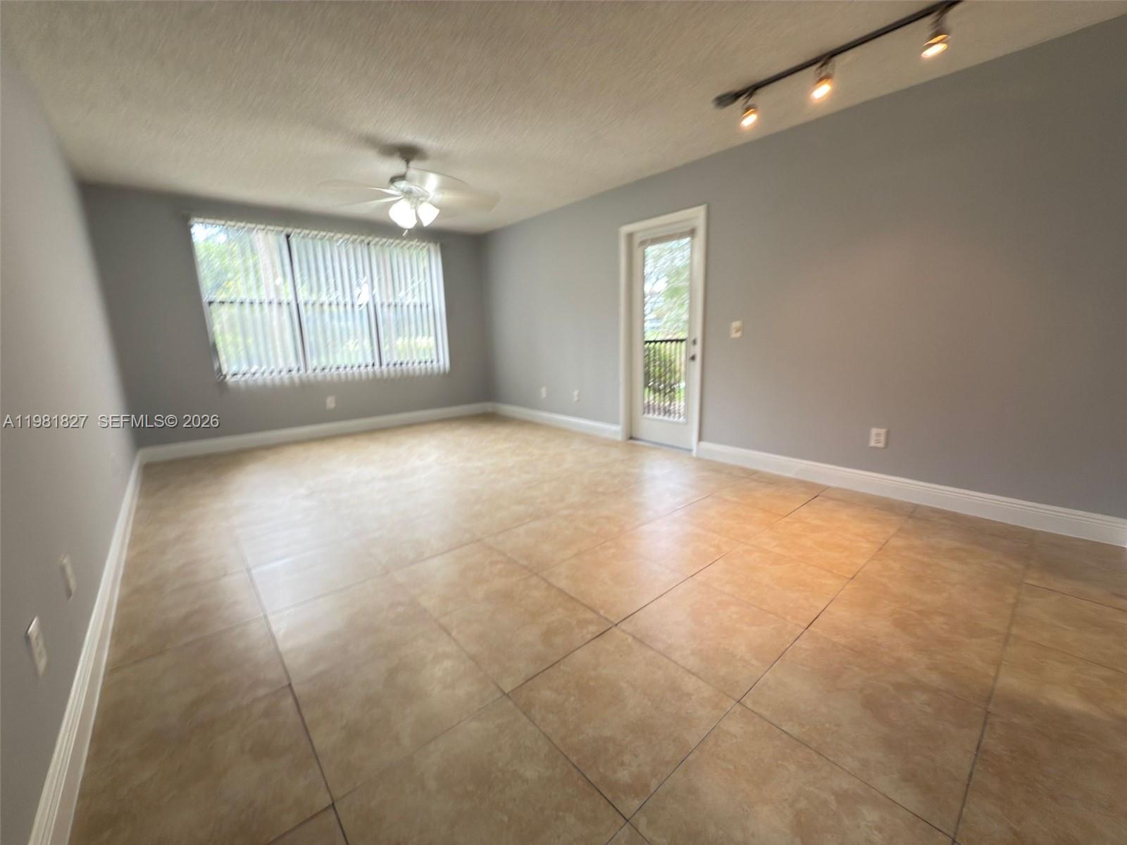 An unfurnished room features light gray walls, large beige floor tiles, and a ceiling fan — 4521 W Mcnab Rd # 11, Pompano Beach FL 33069, POMPANO BEACH, FL