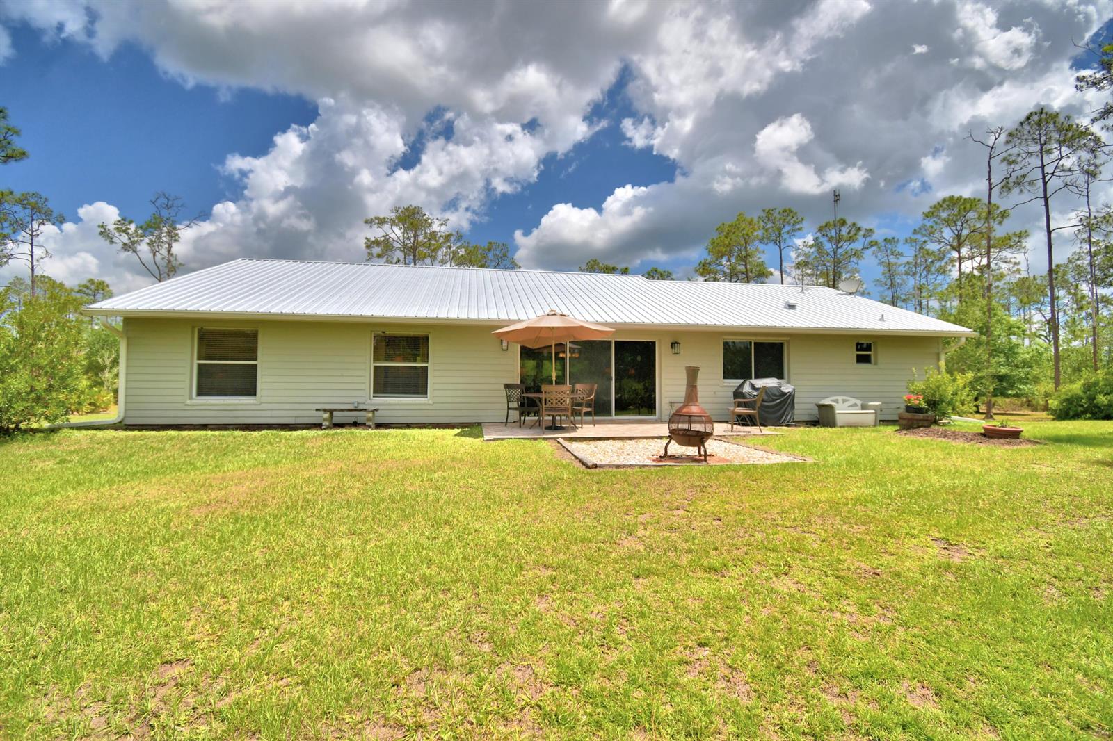 A single-story house with a metal roof, patio, and backyard in a wooded setting — 32801 Hwy 441 N # 36, Okeechobee FL 34972, OKEECHOBEE, FL