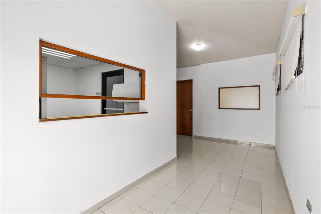 A room with white walls, tiled floors, a wooden pass-through window, and a door — 141 O'NEILL, SAN JUAN, PR