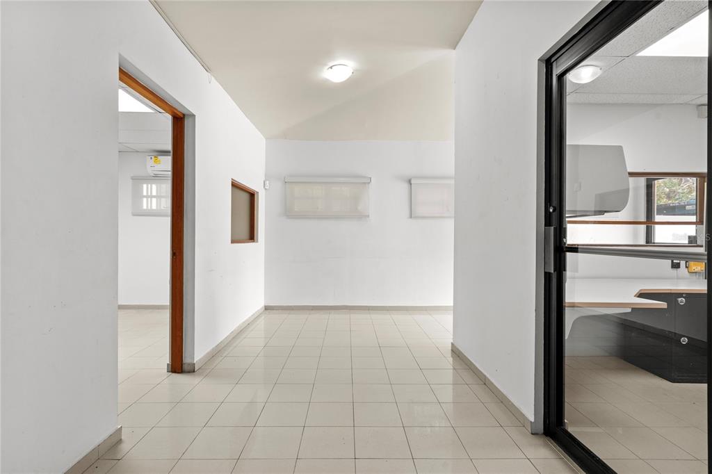 A hallway with white walls and light-colored tile flooring leads toward an open office space — 141 O'NEILL, SAN JUAN, PR