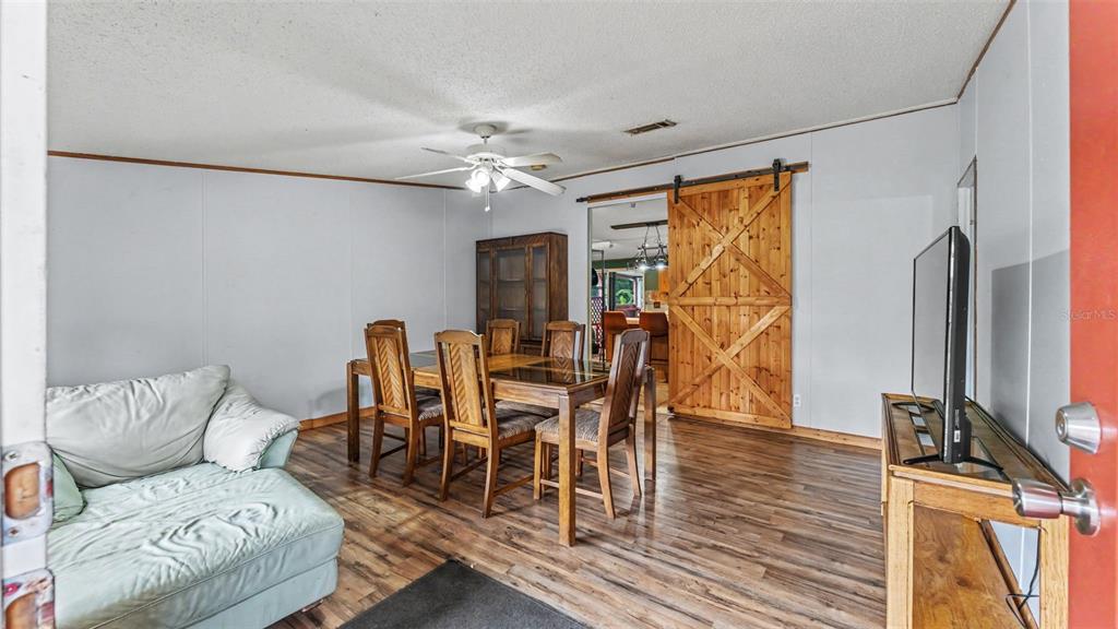 A dining room features wood-look flooring, a wooden dining set, and a sliding barn door — 6702 FORESTVIEW LANE, LAKELAND, FL