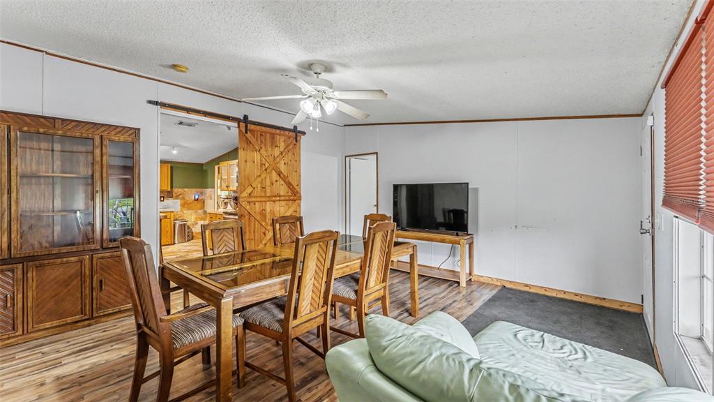 A dining area with a wooden table, chairs, and a sliding barn door to the kitchen — 6702 FORESTVIEW LANE, LAKELAND, FL