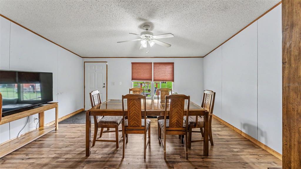 A dining room features a wooden table with six chairs, wood-look flooring, and a ceiling fan — 6702 FORESTVIEW LANE, LAKELAND, FL